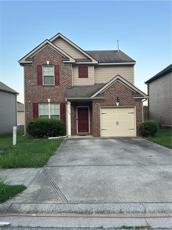 5752 Little River Rd, Atlanta, GA 30349 - traditional-style home with driveway, an attached garage, and brick siding