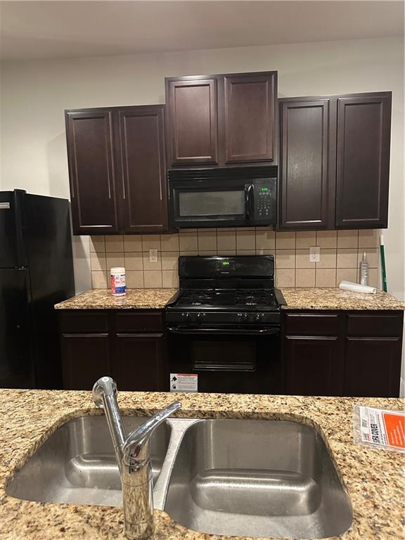 5752 Little River Rd, Atlanta, GA 30349 - kitchen featuring black appliances, dark brown cabinetry, light stone counters, and backsplash