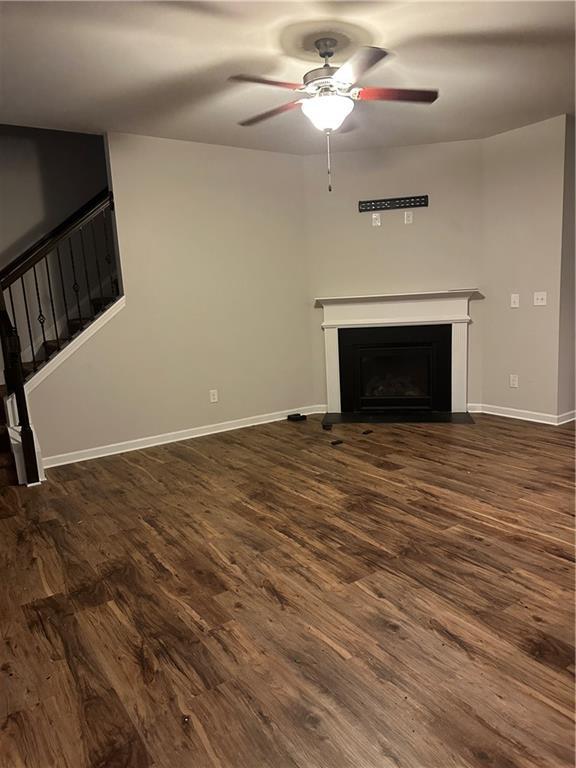 5752 Little River Rd, Atlanta, GA 30349 - unfurnished living room with a ceiling fan, a fireplace, dark wood-type flooring, and stairs