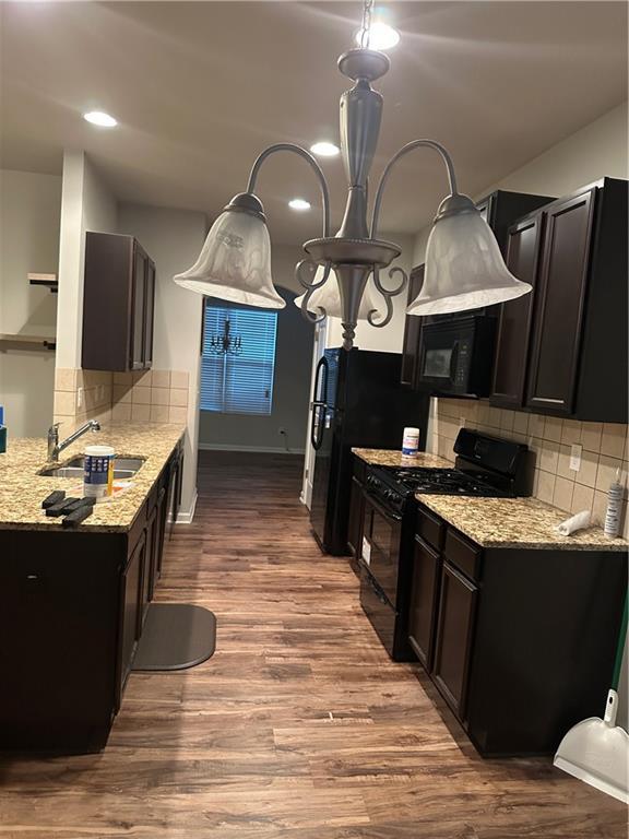 5752 Little River Rd, Atlanta, GA 30349 - kitchen with black appliances, wood finished floors, light stone counters, backsplash, and recessed lighting
