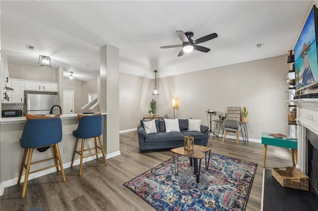 7077 Biltmore Trce, Lithonia, GA 30058 - living area with a ceiling fan, a fireplace, wood finished floors, and baseboards