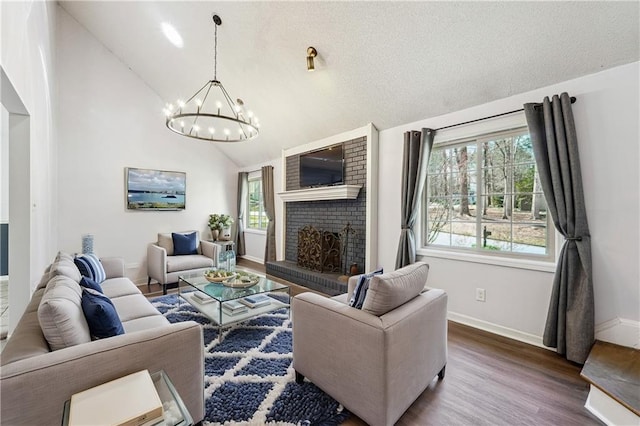 living room featuring wood finished floors, baseboards, a fireplace, a textured ceiling, and a chandelier