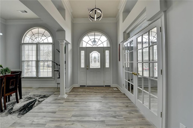 entryway with crown molding, light hardwood / wood-style floors, and ornate columns