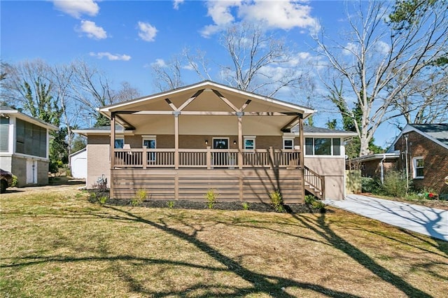 view of front of house with covered porch, a front lawn, concrete driveway, and stucco siding