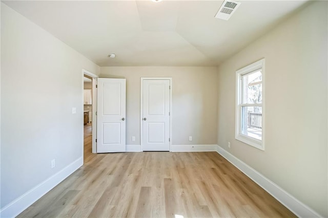 unfurnished bedroom featuring light wood finished floors, baseboards, and visible vents