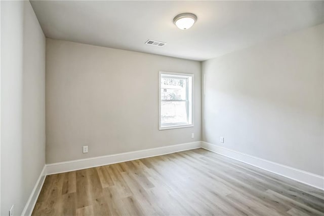 spare room featuring baseboards, visible vents, and light wood-style floors