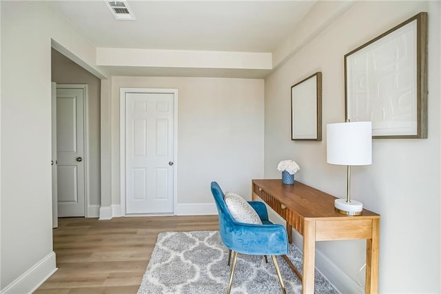 office featuring baseboards, visible vents, and light wood finished floors