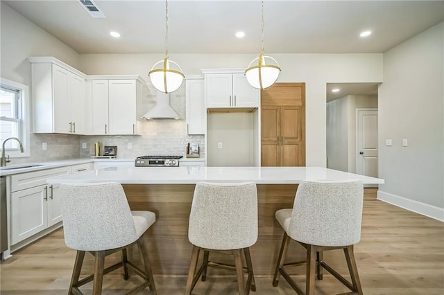 kitchen with pendant lighting, a center island, white cabinets, and light countertops