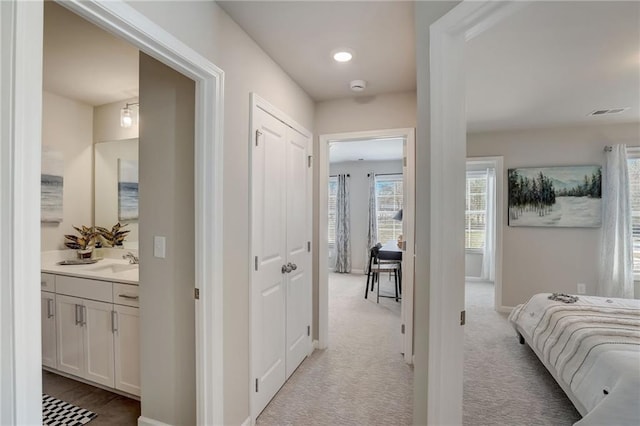 hallway with sink and light carpet