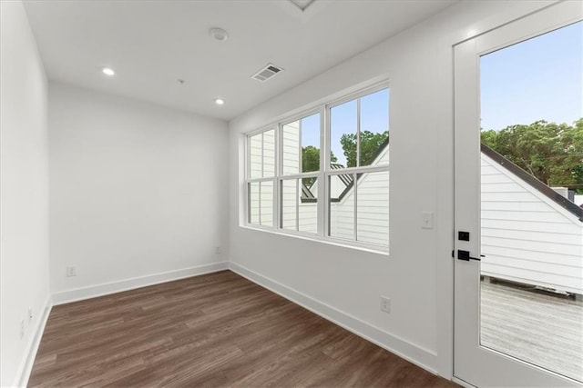 spare room with plenty of natural light and dark hardwood / wood-style flooring