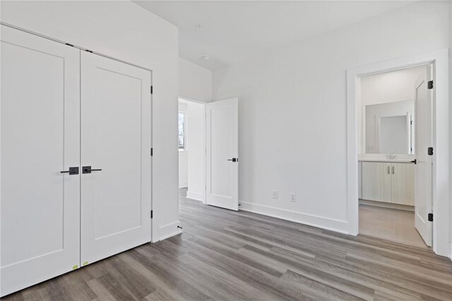 unfurnished bedroom with light hardwood / wood-style floors, a closet, and connected bathroom