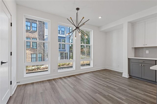 unfurnished dining area with an inviting chandelier and light hardwood / wood-style floors