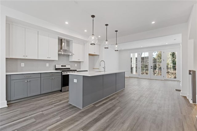 kitchen featuring gray cabinetry, wall chimney exhaust hood, stainless steel gas range, sink, and white cabinetry