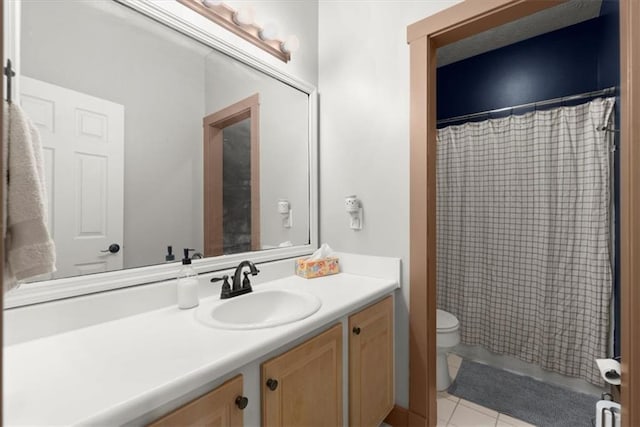 bathroom with toilet, vanity, and tile patterned floors