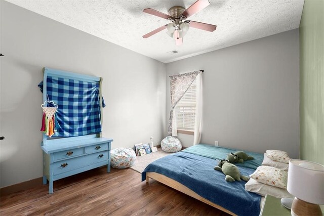 bedroom with a textured ceiling, hardwood / wood-style flooring, and ceiling fan