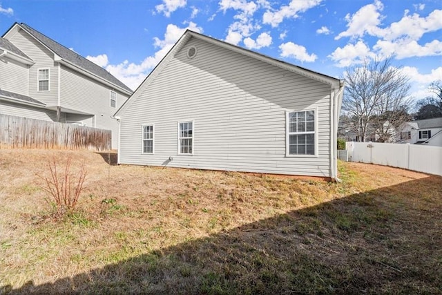 rear view of house with central AC unit and a lawn