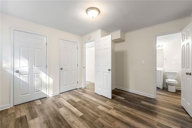 unfurnished bedroom featuring hardwood / wood-style floors, ensuite bathroom, and crown molding