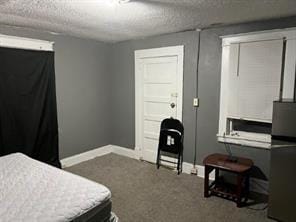 carpeted bedroom featuring stainless steel fridge and a textured ceiling