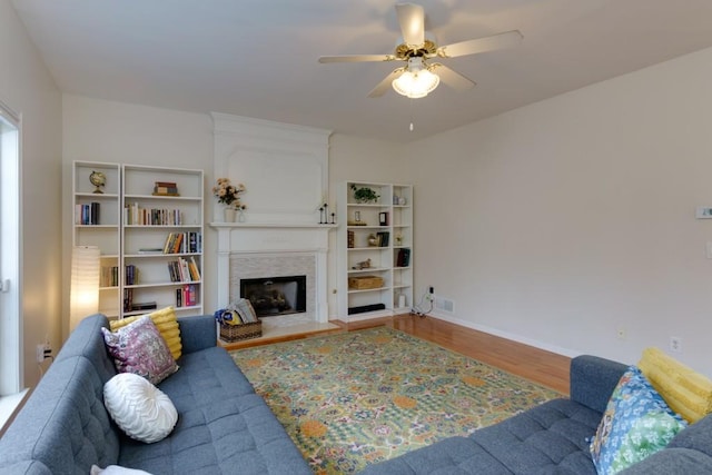 living room with visible vents, ceiling fan, baseboards, a fireplace, and wood finished floors