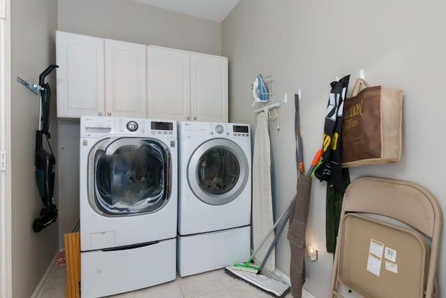 laundry area featuring washer and clothes dryer, light tile patterned floors, and cabinet space