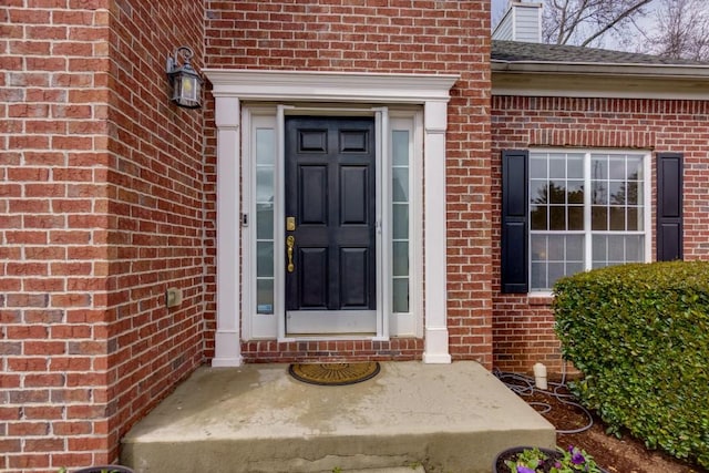 doorway to property featuring brick siding and a chimney