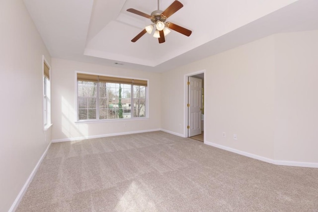 unfurnished room with a tray ceiling, carpet floors, baseboards, and ceiling fan