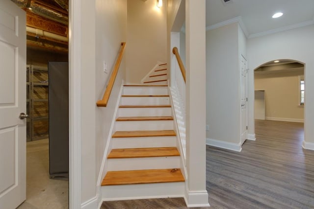 staircase featuring wood finished floors, recessed lighting, arched walkways, crown molding, and baseboards