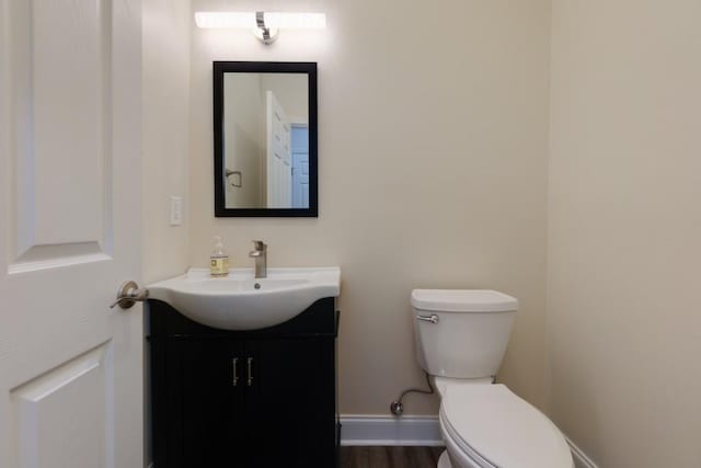 bathroom featuring toilet, vanity, baseboards, and wood finished floors