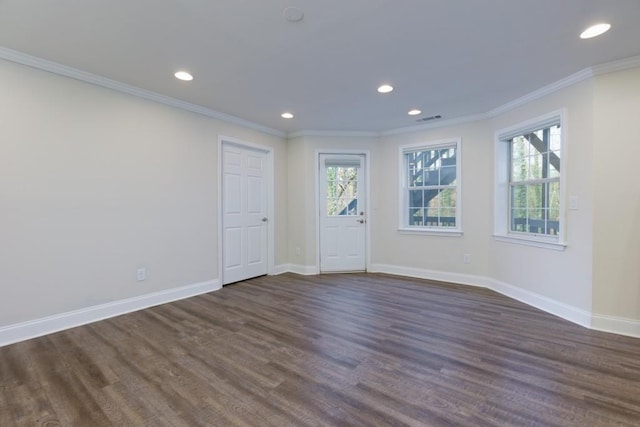 unfurnished room with visible vents, baseboards, dark wood-type flooring, and ornamental molding