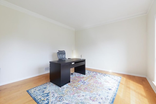 office with visible vents, light wood-type flooring, baseboards, and ornamental molding