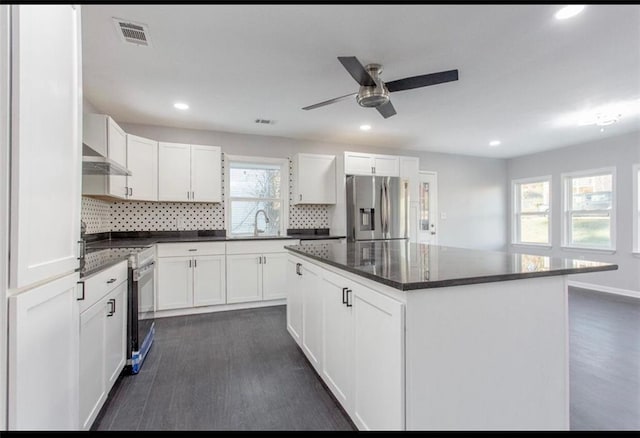 kitchen featuring wall chimney range hood, sink, white cabinetry, a kitchen island, and stainless steel fridge with ice dispenser