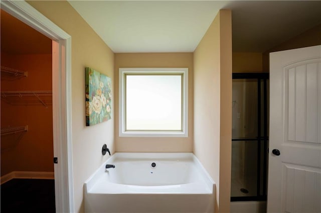 bathroom with a stall shower, a bath, and a spacious closet