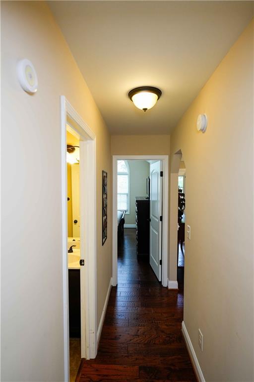 hall featuring dark wood-type flooring and baseboards