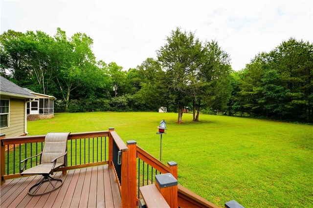 wooden deck featuring a yard, view of scattered trees, and a sunroom