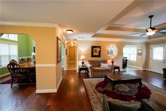 living room with arched walkways, dark wood-style floors, baseboards, and ornamental molding