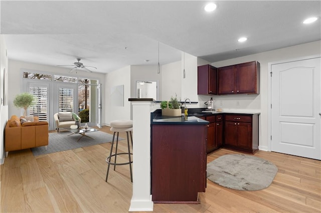 kitchen with light wood-type flooring, a peninsula, open floor plan, and a breakfast bar