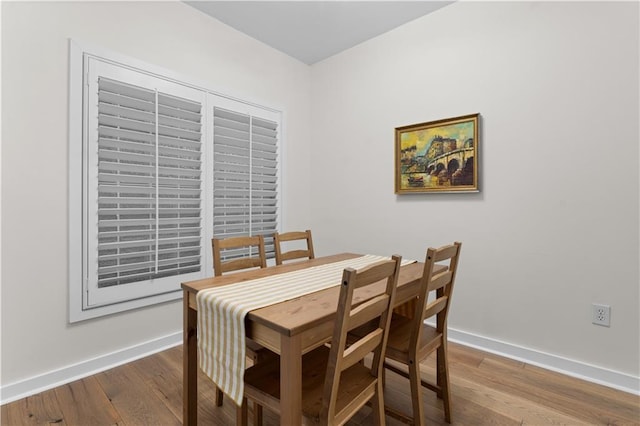 dining space with baseboards and wood finished floors