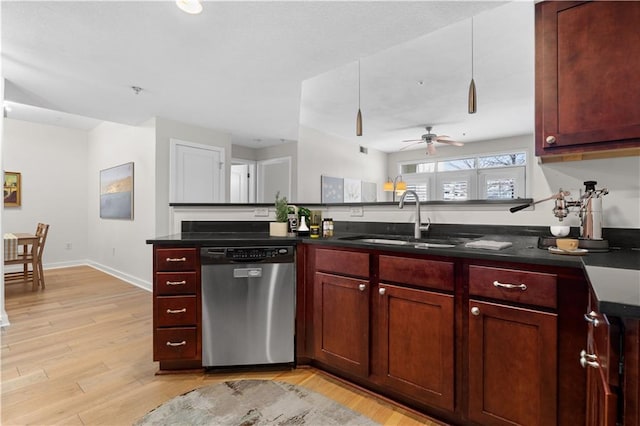 kitchen with a sink, stainless steel dishwasher, dark countertops, light wood-type flooring, and reddish brown cabinets