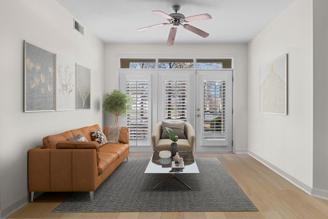 living area featuring ceiling fan, wood finished floors, visible vents, and baseboards