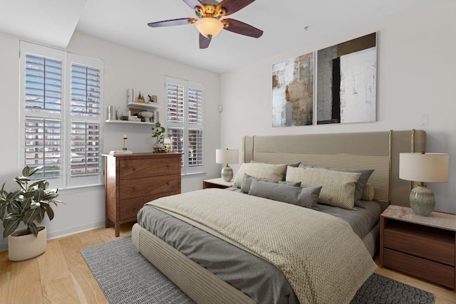 bedroom with a ceiling fan, wood finished floors, and baseboards