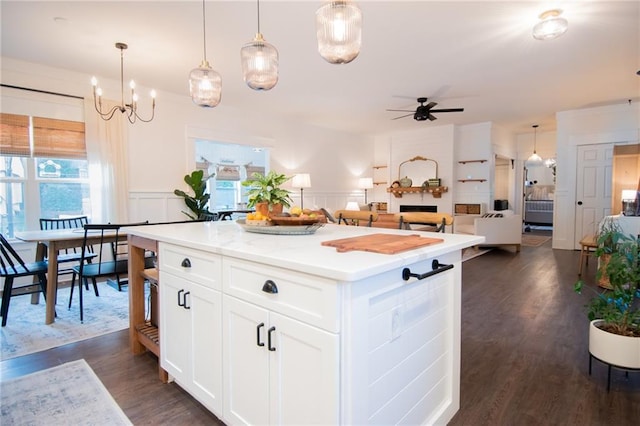 kitchen featuring ceiling fan, white cabinets, pendant lighting, dark hardwood / wood-style floors, and a center island