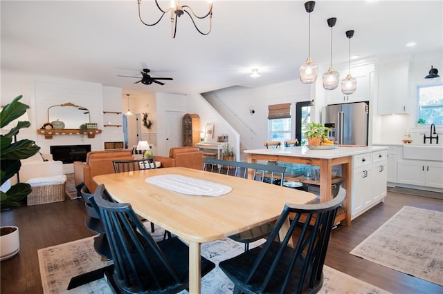 dining area featuring ceiling fan with notable chandelier, sink, and dark hardwood / wood-style flooring