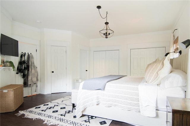 bedroom featuring two closets, dark wood-type flooring, and a chandelier