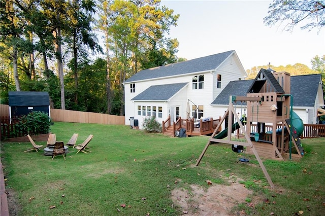 back of house featuring a playground, a storage shed, and a lawn