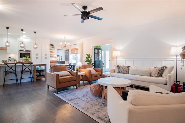 living room with ceiling fan with notable chandelier and dark hardwood / wood-style floors