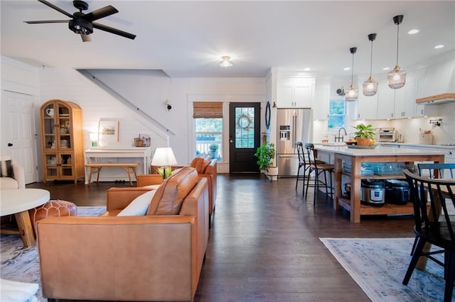 living room featuring ceiling fan, sink, and dark hardwood / wood-style flooring