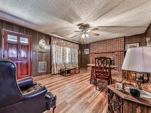 6267 Mount Pisgah Rd, Ellijay, GA 30540 - living area with a textured ceiling, wood finished floors, wood walls, a fireplace, and ceiling fan