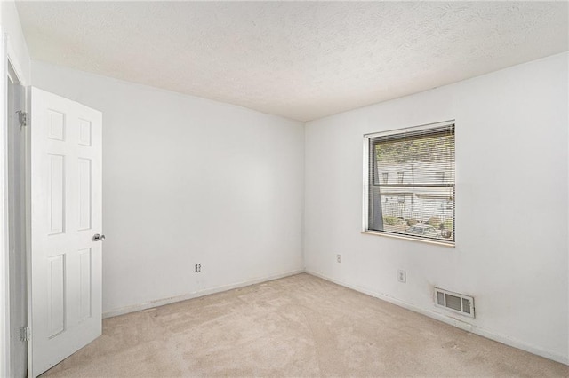 empty room featuring baseboards, visible vents, light carpet, and a textured ceiling