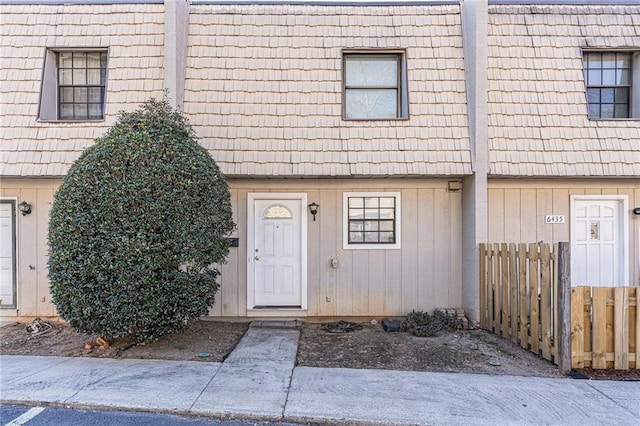 view of exterior entry featuring mansard roof and fence