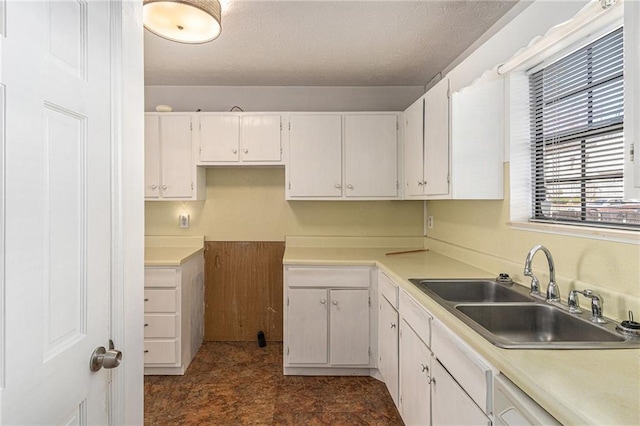 kitchen featuring light countertops, white cabinetry, a sink, and white dishwasher